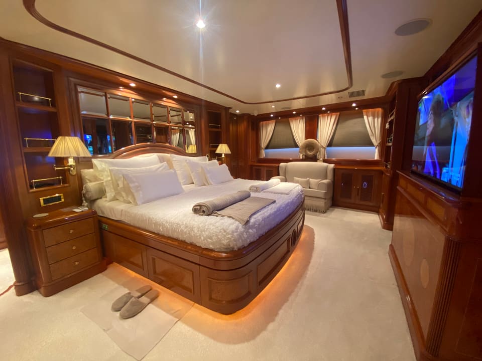 2003 Benetti Classic 115 – master cabin with king bed, warm wood joinery, armchair, TV and soft under-bed lighting