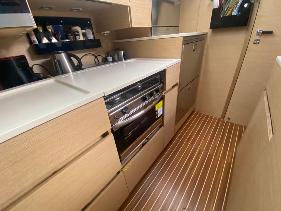 2018 Hanse 548 – galley with white countertops, gas hob and oven, light wood cabinetry and teak-style sole