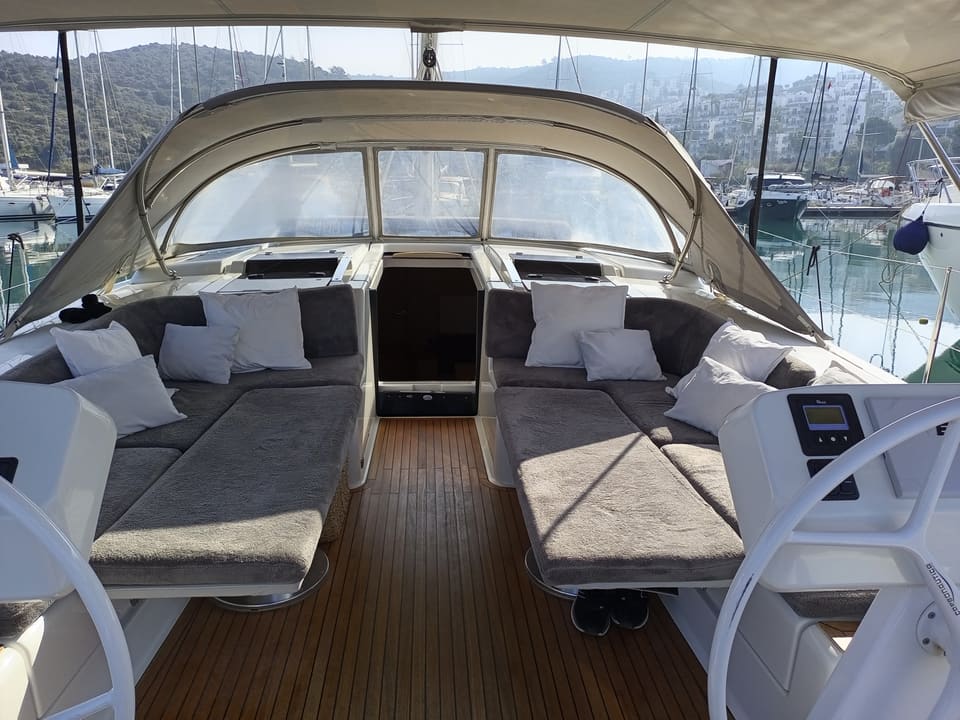 2022 Hanse 508 – cockpit with grey cushioned lounges, teak sole, twin helm wheels and sprayhood