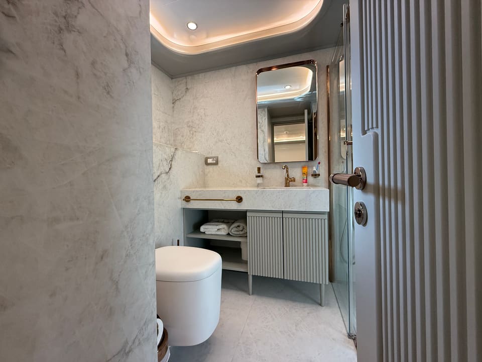 2023 Custom Laminated Motorsailer 41M – marble bathroom with fluted vanity, backlit mirror, wall-hung toilet and glass shower