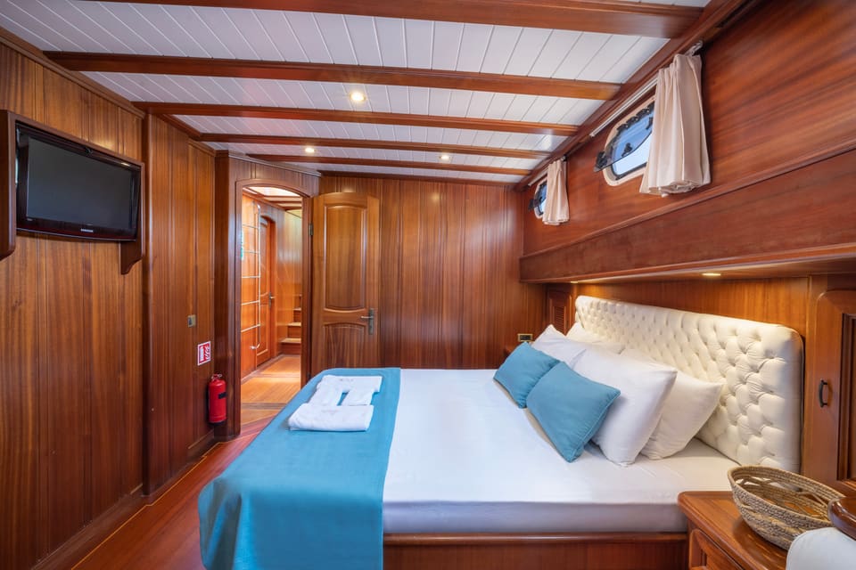 2009 Custom Ketch 31M – wood-panelled cabin with double bed, tufted headboard, portholes and wall-mounted TV