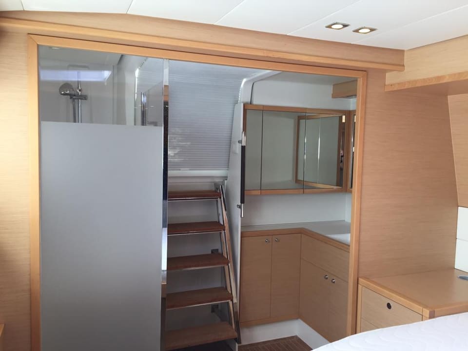 2015 Lagoon 560 S2 – duşlu banyosu, aynalı lavabo dolabı ve güverteye çıkan ahşap merdiveniyle tekne sahibi kabini