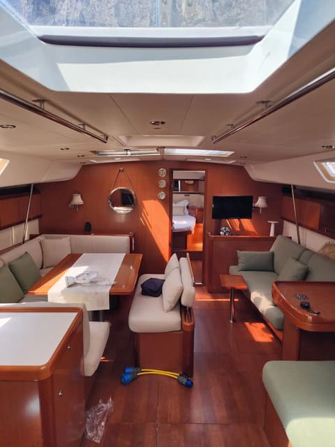 2009 Beneteau Oceanis 54 – kiraz ağacı mobilyalı salon, yemek masası, kanepeler, TV ve tavan kaportaları