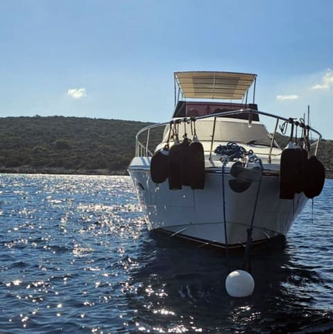 2005 Ferretti 530 – bow view at anchor with flybridge bimini, fenders and mooring buoy on calm water