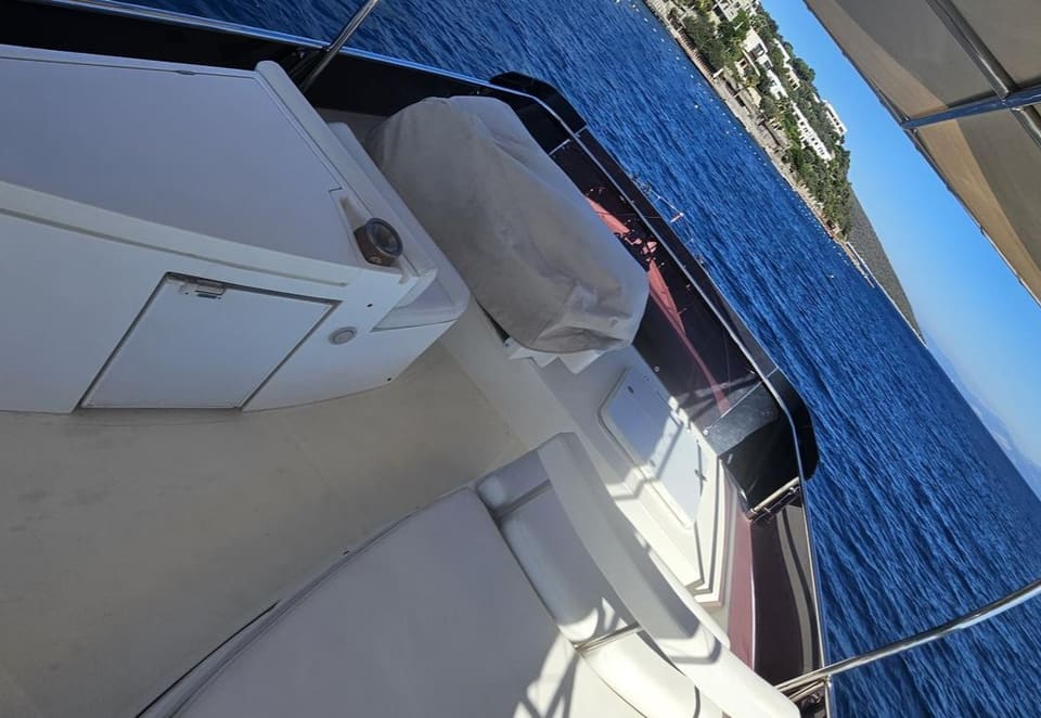2005 Ferretti 530 – flybridge with white cushioned seating, wet bar unit, covered helm seat and bimini top over open sea