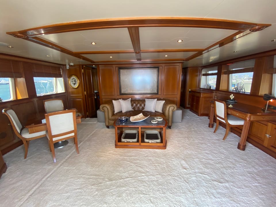 2003 Benetti Classic 115 – main saloon with warm wood panelling, leather Chesterfield sofa, coffee table and writing desk