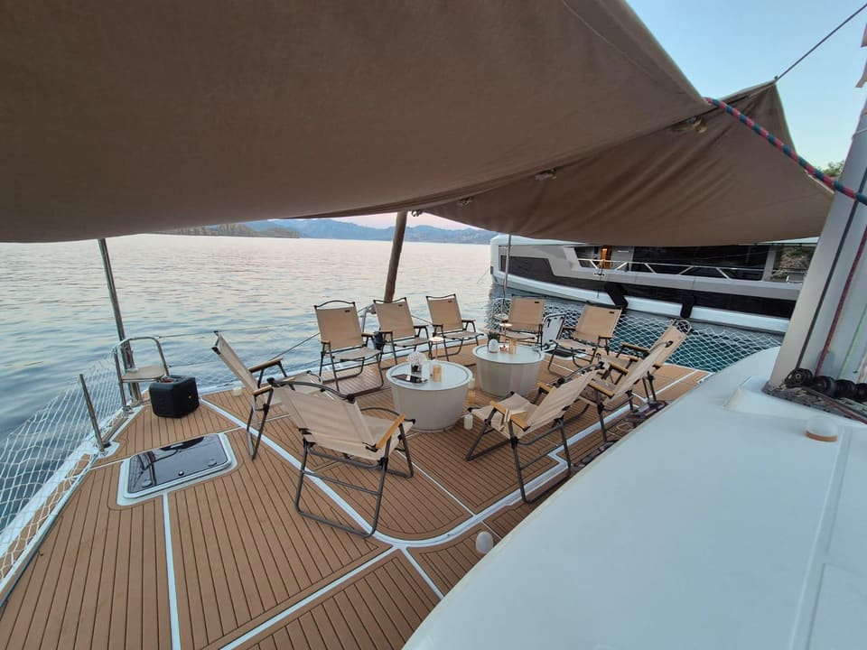 2010 Lagoon 400 – shaded foredeck with folding chairs, round tables and teak-style decking