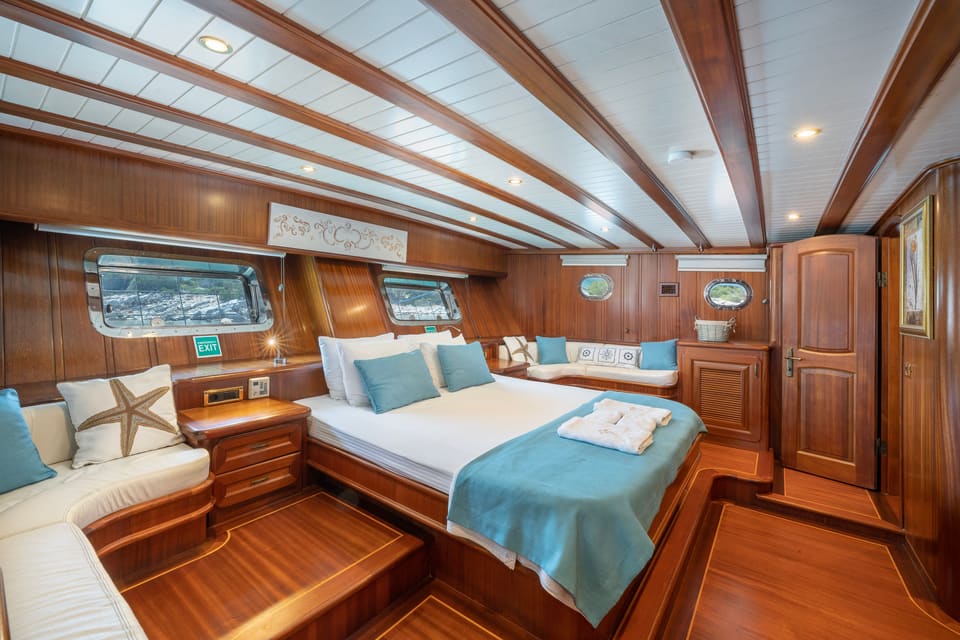 2009 Custom Ketch 31M – master cabin with wooden interior, double bed, sofa seating and portholes