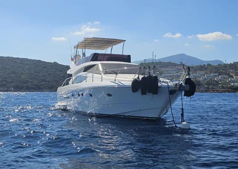 2005 Ferretti 530 – white motor yacht at anchor with flybridge bimini, side fenders and wooded hills behind