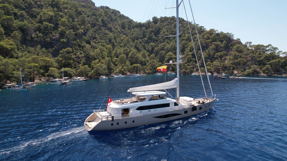 2023 Custom Laminated Motorsailer 41M – aerial view under way with tall mast, furled sails and spacious decks on deep blue water