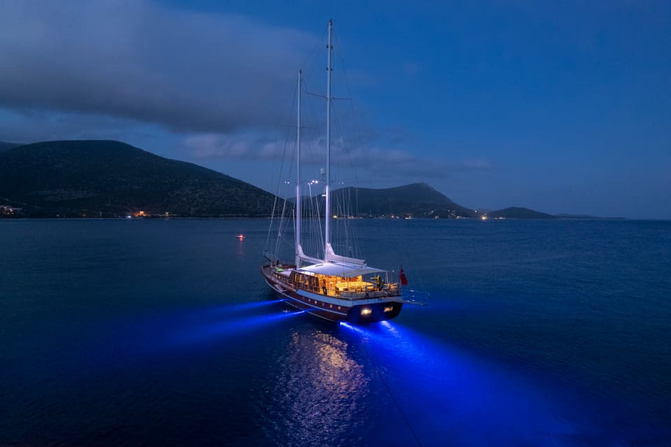 2009 Custom Ketch 31M – aerial dusk view at anchor with blue underwater lights and illuminated deck