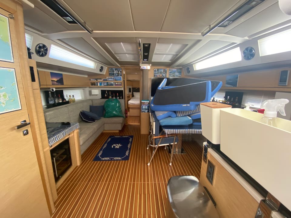 2018 Hanse 548 – saloon with L-shaped sofa, teak-style floor, wine cooler and view forward to cabin