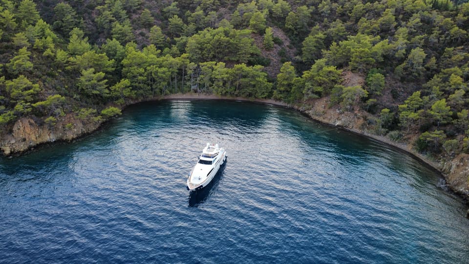 2007 Custom Line 97 – çam ağaçlarıyla çevrili sakin bir koyda demirli yatın havadan görünümü