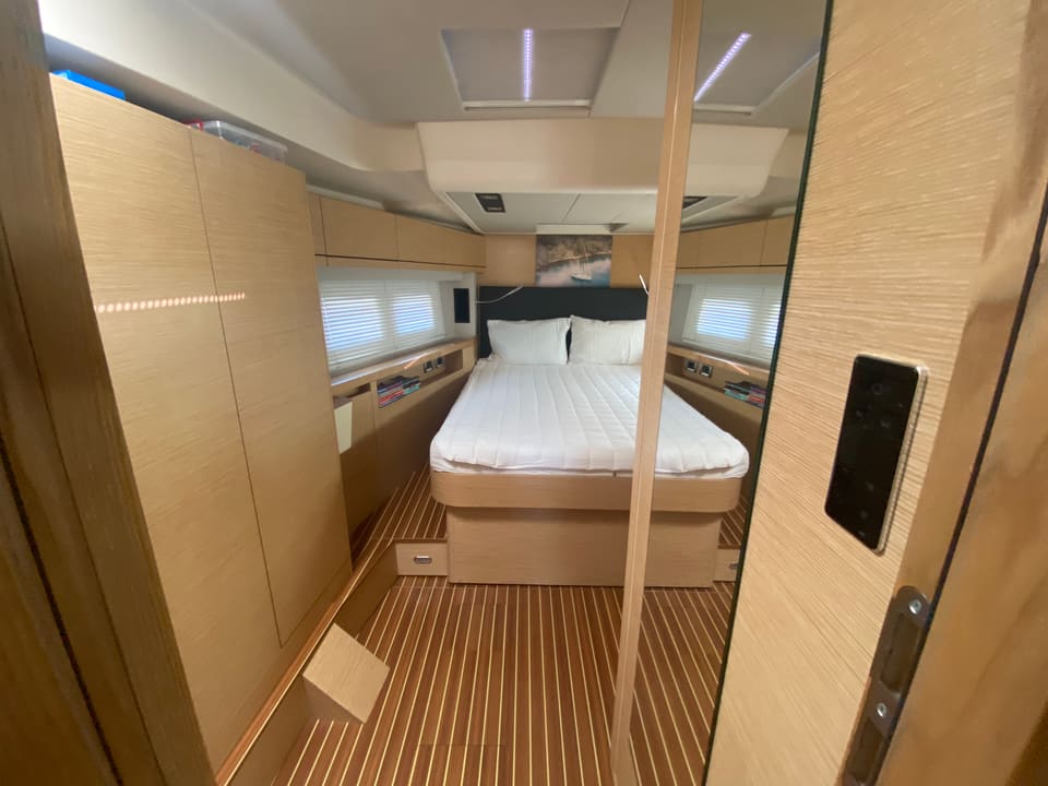 2018 Hanse 548 – master cabin with island double bed, light oak joinery, teak-style floor and hull windows