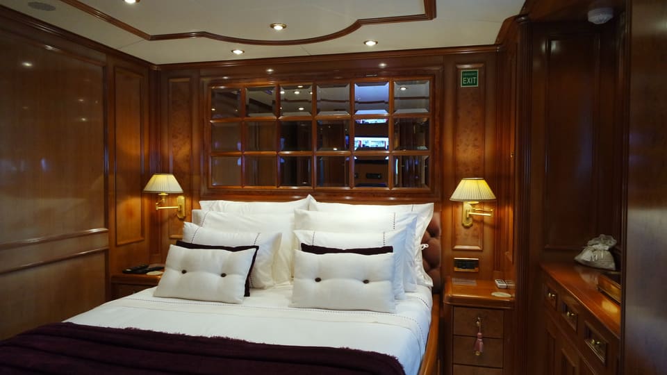 2003 Benetti Classic 115 – guest cabin with double bed, warm wood panelling, mirrored headboard and brass wall lamps
