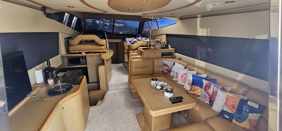 2005 Ferretti 530 – saloon with leather sofa, wooden table, galley counter and lower helm forward