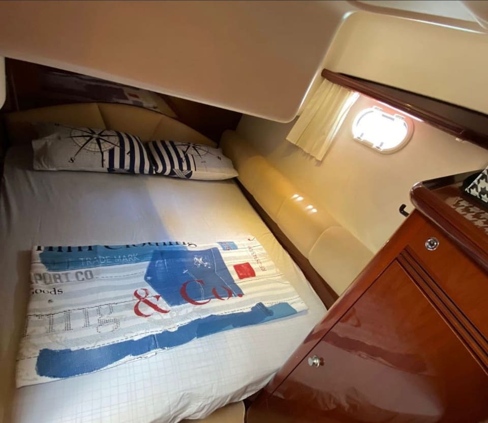 2002 Prestige 46 – guest cabin with double , nautical cushions, porthole light and glossy cherry wood cabinetry