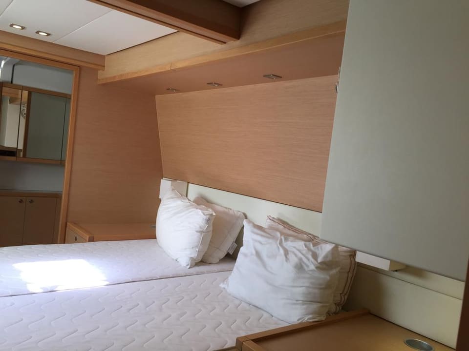 2015 Lagoon 560 S2 – çift kişilik yataklı, açık renk ahşap kaplamalı ve üst dolaplı misafir kabini